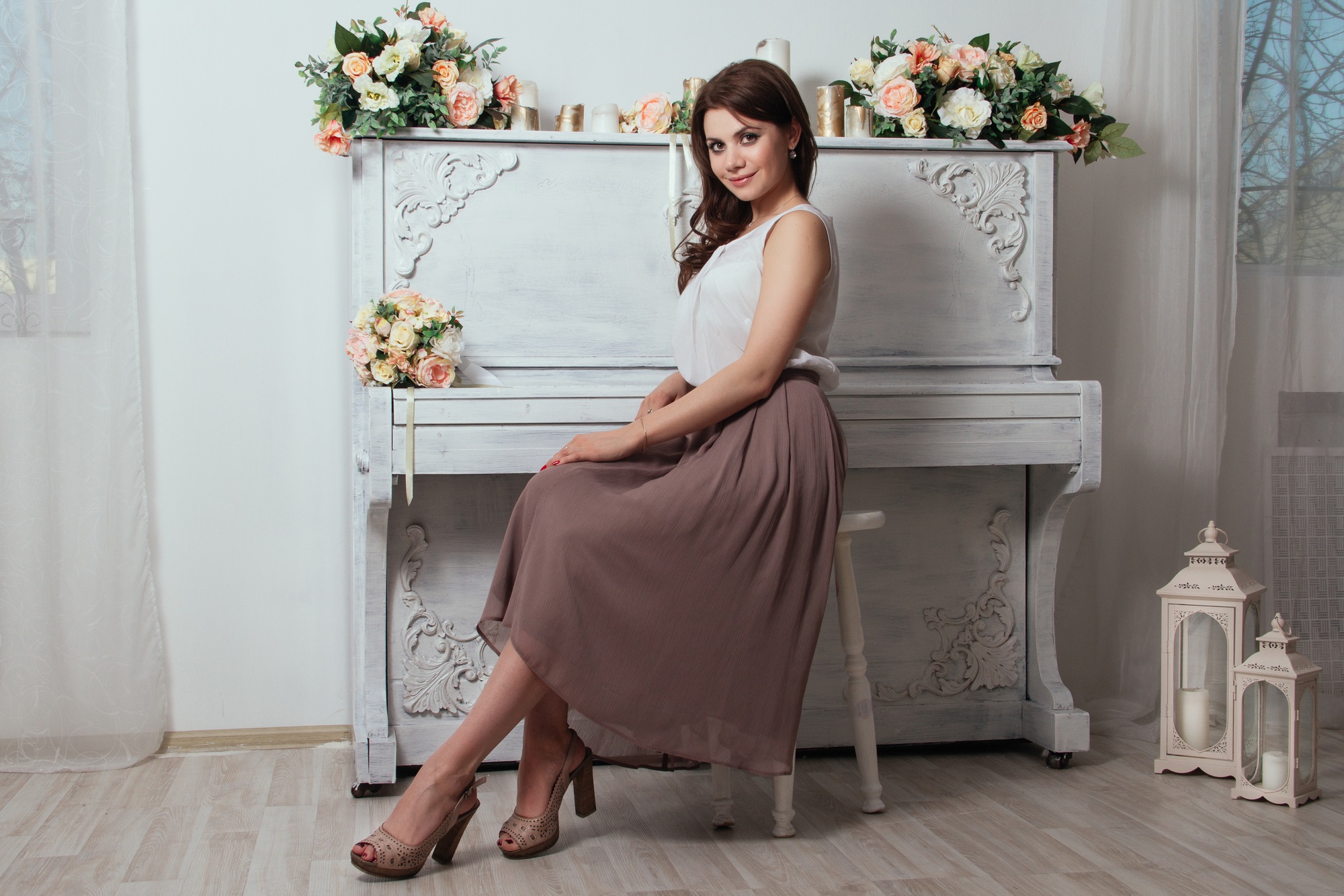Beautiful charming brunette in the house near the old piano on which lay bouquets of roses. Lots of