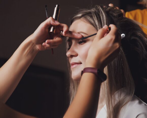 Makeup artist made wedding make-up for cute young woman bride at wedding day in hotel room