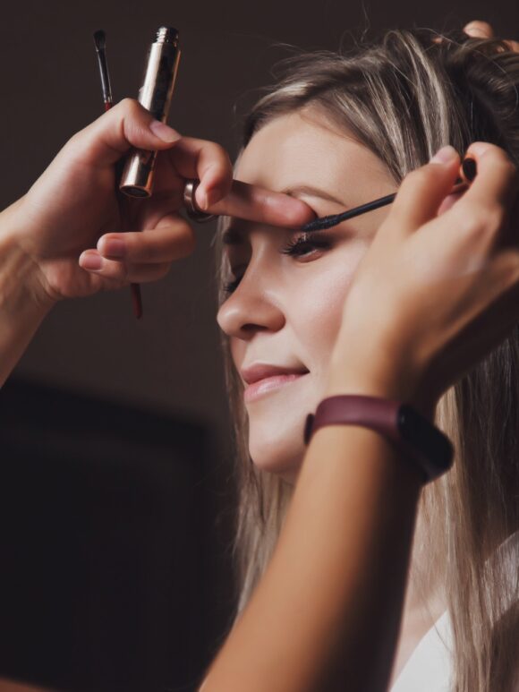 Makeup artist made wedding make-up for cute young woman bride at wedding day in hotel room