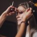 Makeup artist made wedding make-up for cute young woman bride at wedding day in hotel room