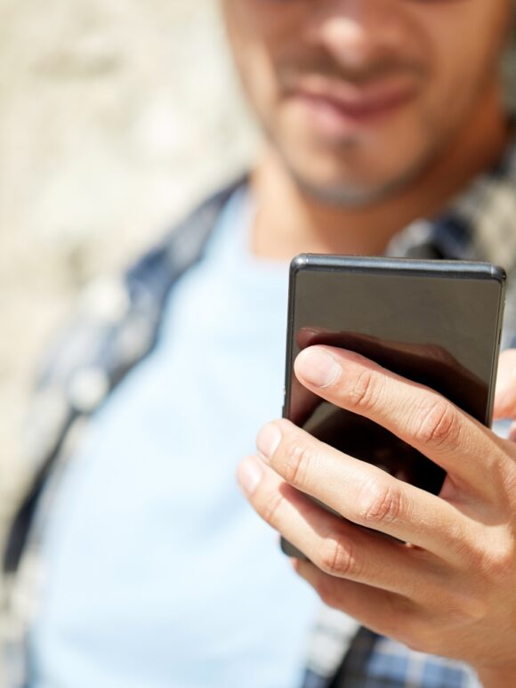 man with smartphone texting message outdoors