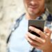 man with smartphone texting message outdoors