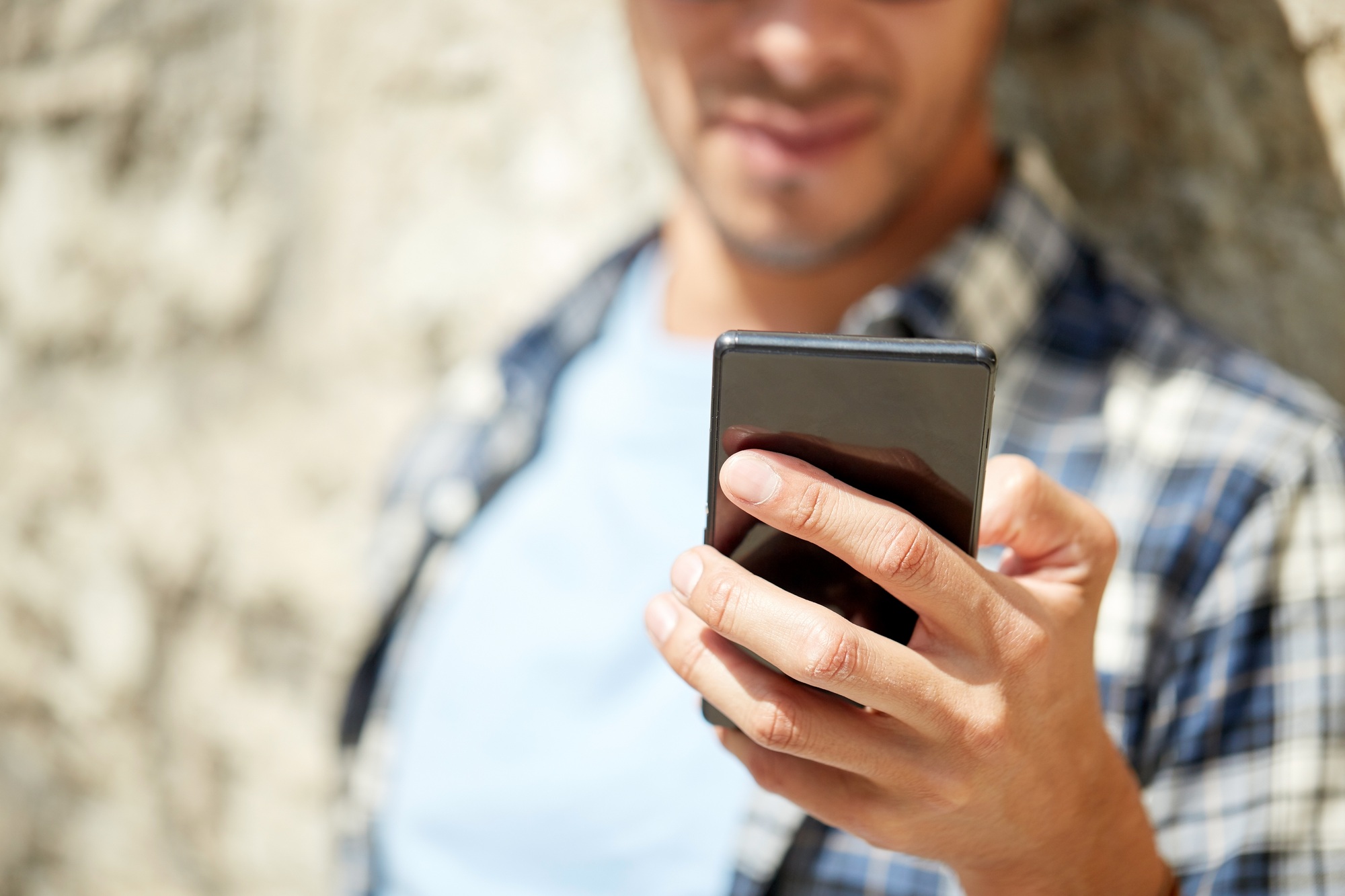man with smartphone texting message outdoors